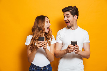 photo of positive excited people man and woman screaming and looking at each other while both using 