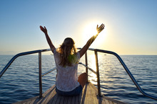 Woman On A Yacht Looking Out Into The Beautiful Sunset, Hands Into Sky