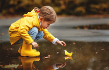 Happy Child Girl With Umbrella And Paper Boat In   Puddle In   Autumn On Nature.