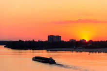 Tugboat Pushing A Heavy Long Barge On The River Dnieper At Sunset