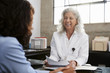 © Monkey Business - Smiling female doctor in consultation with patient in office