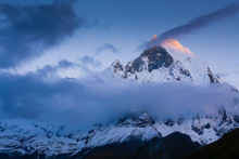 Machapuchare Peak On The Annapurna Range At Sunset Enveloped In Clouds.