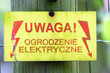 Warning sign with a live fence in polish language (uwaga ogrodzenie elektryczne pod napieciem).