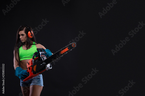 Fotografie, Obraz Studio photography of a girl with a chain saw on dark background