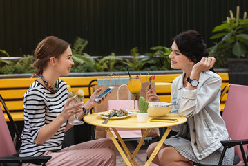 Wall Mural - Informal meeting. Two promising fashion designers feeling joyful while having informal meeting in cafe