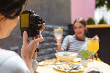 Wall Mural - Photographer with camera. Dark-haired professional photographer holding her camera while working hard