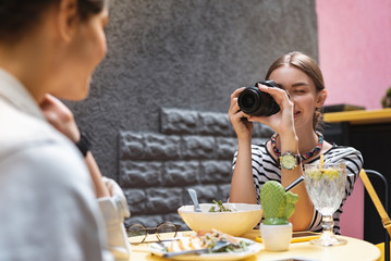 Wall Mural - Joyful occupation. Skillful experienced photographer enjoying her occupation while making photo of friend