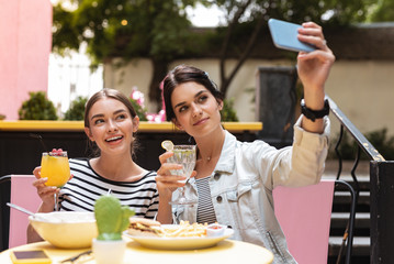 Wall Mural - Two businesswomen. Two prosperous successful businesswomen making photo while having lunch together