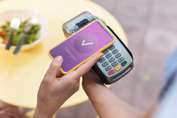 Wall Mural - Pay pass. Modern woman paying for her salad while holding her smart phone in hand