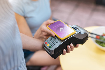 Wall Mural - Paying for order. Prosperous businesswoman putting her phone to pin pad while paying for order