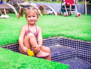 Little beautiful girl resting in the pool and learning to swim