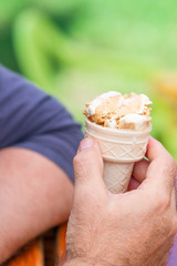 Sticker - Hand of a male holding an ice cream in a waffle - closeup with  selective focus