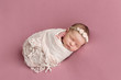 Sleeping newborn girl on a pink background. Photoshoot for the newborn. 7 days from birth. A portrait of a beautiful, seven day old, newborn baby girl