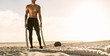 © Jacob Lund - Man standing on the beach holding battling ropes for workout