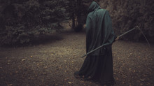 Death, Grim Reaper, With His Scythe Lurking In The Woods In A Haunted Forest