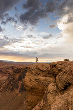 A Man Standing On The Edge Of Horse Shoe Bend