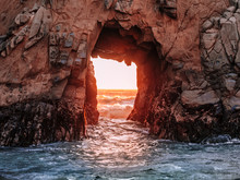 Stunning View Of The Pacific Ocean Through An Opening In The Rocky Cliff At Pfeiffer Beach, Near Big Sur, California. Rocks Colored Red By The Sunset And Covered With Algae. Glowing Gates To The Sea.