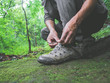 Hiker tying boot laces on green moss trail relax and enjoy in forest