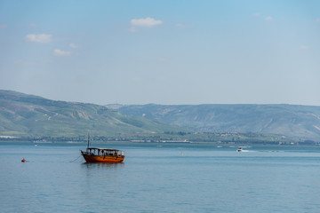 Old boat on Sea of Galilee in Israel at foggy spring day.