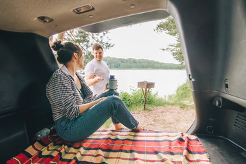 Wall Mural - couple resting outside. car travel concept. sitting in trunk