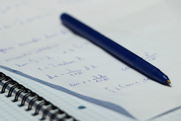 A blue pen with small exercise book and different make a calculation in math on university. A small iron circle attaching papers