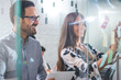 © Bojan - Businessman and businesswoman sticking adhesive notes on glass wall in office