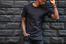 Man In Blank Black T-shirt Standing Against Brick Wall, Cropped Shot