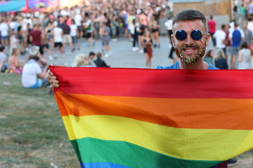 Man with glitter beard holding rainbow flag