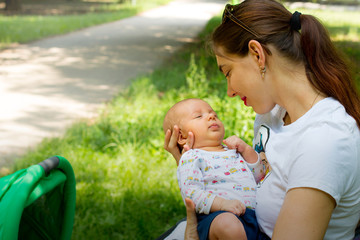 mother and child, happy young woman is holding her cute baby in the hands, loving mother smiling and