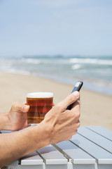 Wall Mural - drinking a beer and using a phone on the beach