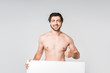 © LIGHTFIELD STUDIOS - portrait of smiling shirtless man with blank banner showing thumb up isolated on grey