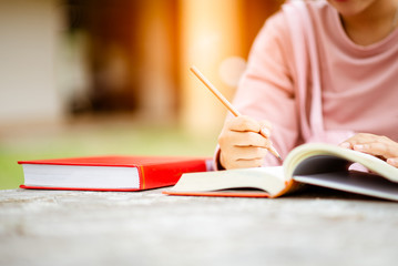 close up of student's hands with books  writing to notebooks.education and school concept