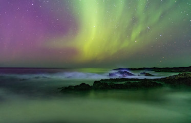 the starry sky and the northern lights above the ocean. milk waves. long exposure.