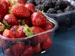 Close-up of blackberries in a plastic container with strawberries.