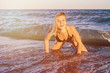 © indigo_nifght - A girl in a black swimsuit posing in the sea standing on the beach on all fours among the raging waves. Toned, the concept of a beach holiday and a healthy lifestyle.