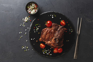 Wall Mural - Rib eye steak on dark plate with thuja