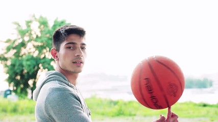 Canvas Print - Young sporty man in the city, spinning basket ball on his finger.