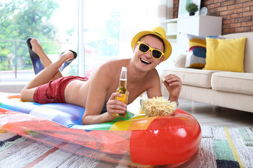 Sticker - Shirtless man with inflatable mattress, drink and popcorn on floor at home