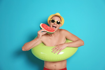 Sticker - Shirtless man with inflatable ring eating watermelon on color background