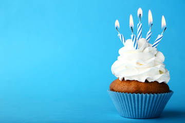 Wall Mural - Tasty cupcake with candles on blue background