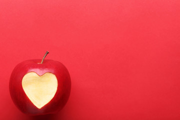 Fresh apple with cutout heart shape on red background