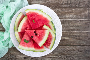 Wall Mural - Slices of a ripe watermelon on a plate on a wooden table. Top view.