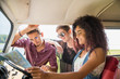 © jackfrog - Mixed group of happy young people in a car looking at a map