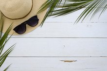 Summer Vacation, Travel, Holiday, Beach Concept. Sun Hat, Sunglasses And Tropical Palm Leaves On White Wooden Board. Top View, Space For Text. Flat Lay Mock Up