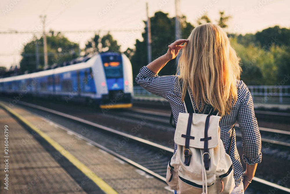 woman is looking at arriving train at a railway station - obrazy, fototapety, plakaty 