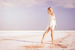 © indigo_nifght - Girl walking on the salt lake, with abstract lines of sand. The concept of tourism, recreation, Spa treatments.