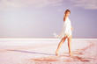 © indigo_nifght - Girl walking on the salt lake, with abstract lines of sand. The concept of tourism, recreation, Spa treatments.