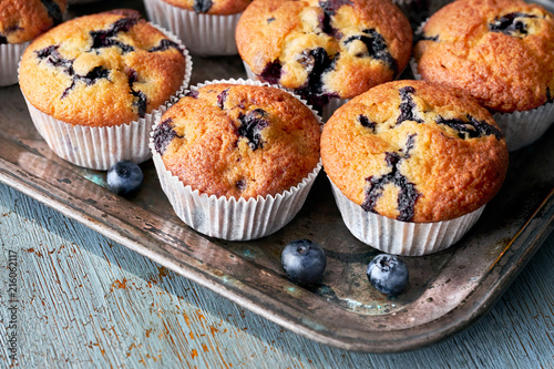 Cuadros en Lienzo Tasty blueberry muffins on old baking tray sitting on rustic wood, text space