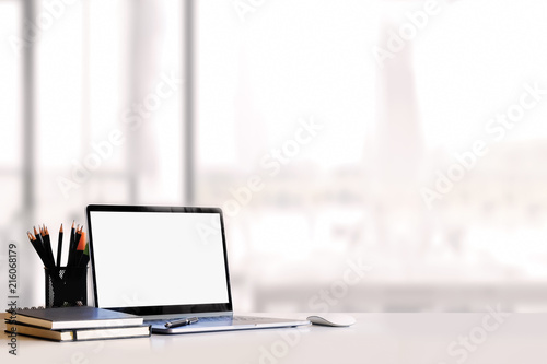 Fotografia Sideview of office desktop with blank laptop and various office tools on wood desk