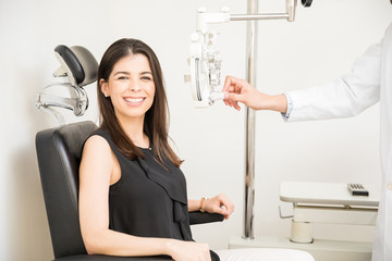 Beautiful woman undergoing eye test with phoropter in optical store